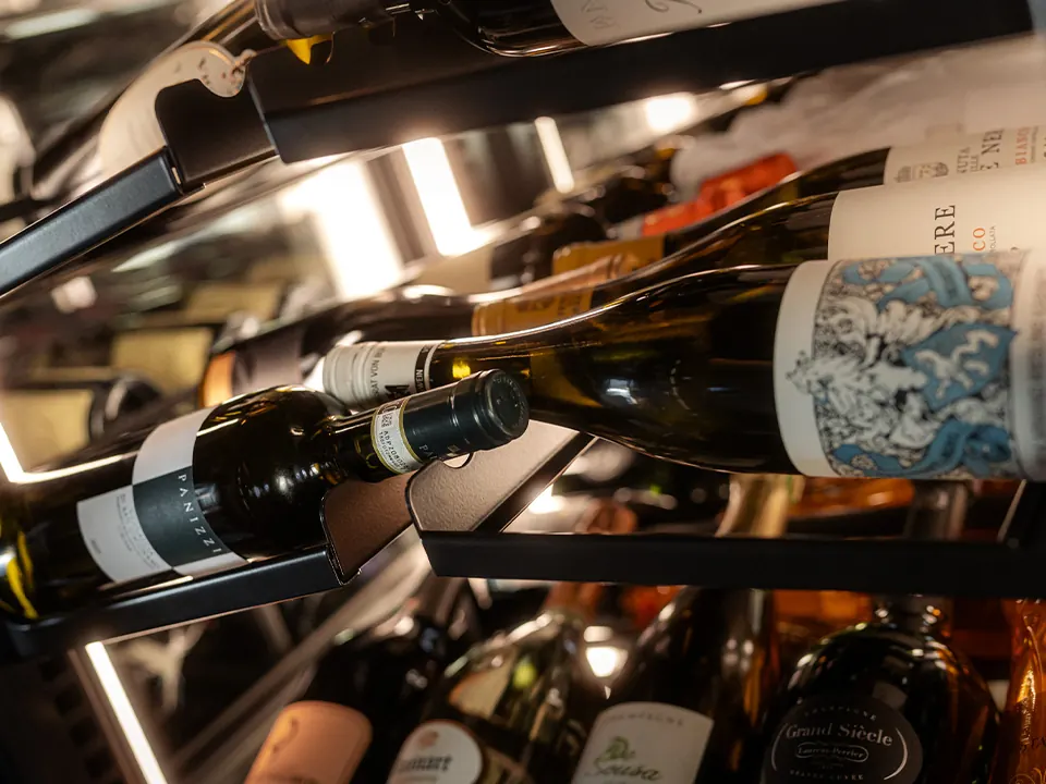 Wijnflessen op de schappen van een verlichte wijnkast